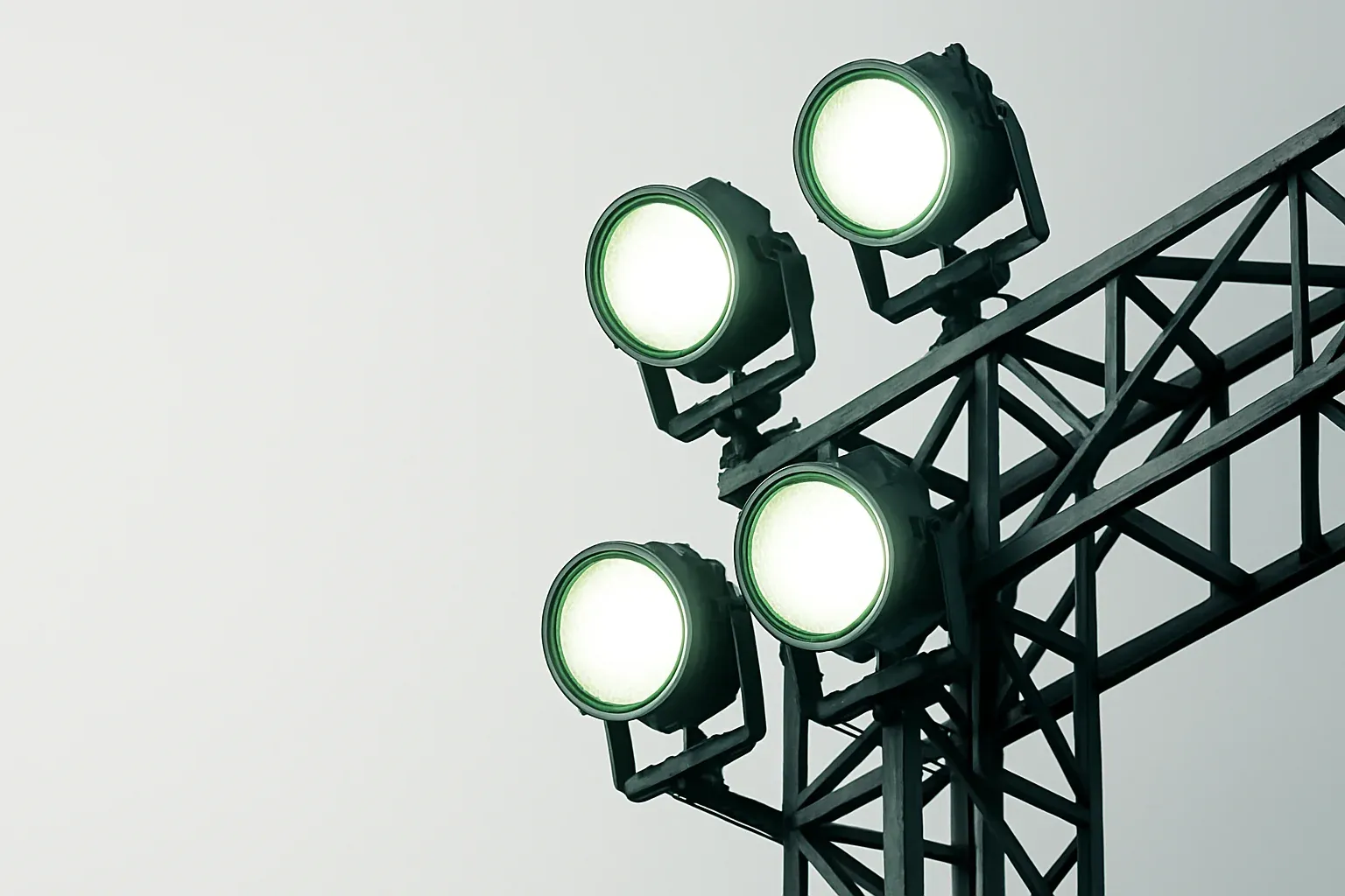 Looking up at four bright stadium floodlights at blue hour